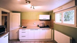 a kitchen with white cabinets and a sink and a window at Cocoon Spa in Issenheim