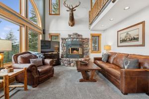 a living room with leather furniture and a stone fireplace at Elk Run in Whitefish