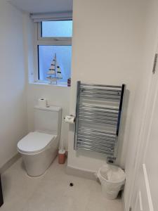 a white bathroom with a toilet and a window at 2 Bed Apartment with Harbour Views Apt 2 in Cobh +4 photos