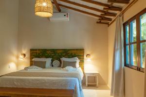 a bedroom with a bed and a large window at Rio Da Barra Villa Hotel in Trancoso