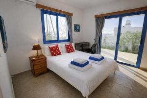 a bedroom with a white bed with red and blue pillows at Livia - Vikles Villas in Pomos