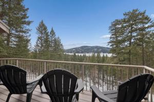 a deck with three chairs and a table and a view at Elk Run in Whitefish