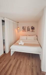 a white bed in a room with a wooden floor at OBOĒ Gardenstē in Pereybere
