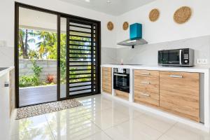 a kitchen with white counter tops and wooden cabinets at Fare Re'are'a - Charmant bungalow côté mer proche de la plage de Temae in Moorea