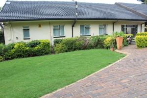 a house with a brick driveway in front of a yard at Sunlit Retreat Private Flatlet with Solar Power Pool Fast WiFi & Secure Parking in Roodepoort