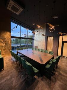 a conference room with a large wooden table and green chairs at Hotel Oasis in Vinnytsya