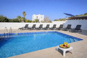 a pool with chairs and a table with a bowl of fruit at Livia - Vikles Villas in Pomos