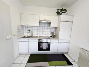 a small kitchen with white cabinets and a green rug at Apartment Kliniknähe in Idar-Oberstein +7 photos
