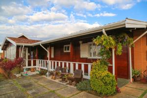 a red house with a porch with chairs and plants at Pousada do Vento in Campos do Jordão