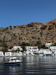 a boat in the water in front of a village at Traditional Villa with pool in Sfakia in Ímbros