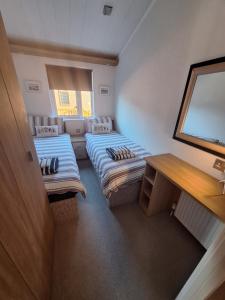 a small room with two beds and a table at Bayview Luxury Lodge in Cockburnspath