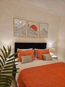 a bedroom with a large bed with orange sheets and pictures at Elite 3 BR Apartment in Zayed in Sheikh Zayed