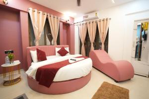 a bedroom with a pink bed and a chair at Elysia By THL-Near Westend Mall Aundh in Pune