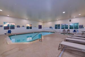a swimming pool in a room with tables and chairs at Comfort Suites Springfield-Eugene in Springfield