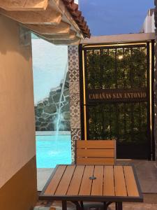 a wooden bench sitting in front of a gate with a fountain at Cabañas San Antonio in Ezequiel Montes