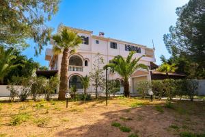 a large pink house with palm trees in front of it at Gkr Luxury Villa in Aghia Marina