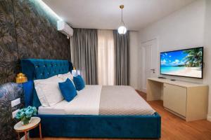 a bedroom with a blue bed and a flat screen tv at Hotel Capital Inn Tirana by Arta in Tirana