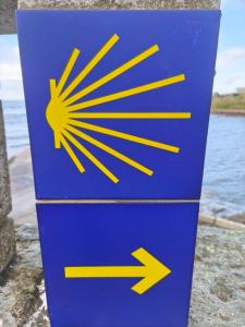 a blue sign with arrows on it next to the water at O refuxio do mar in Oia +78 photos