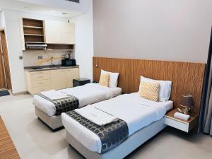 two beds in a hotel room with a kitchen at The Saj Hotel Apartments in Ras al Khaimah