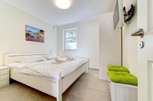 a white bedroom with a white bed and a window at Strandvej in Prerow