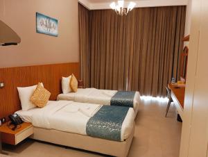 a hotel room with two beds and a window at The Saj Hotel Apartments in Ras al Khaimah
