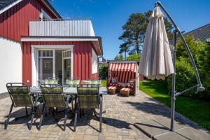 a patio with a table and an umbrella and chairs at Dreimäderlhaus in Prerow