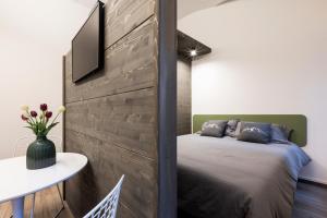 a bedroom with a bed and a tv on a wall at Ca' Lumaga -Charming Holiday Studio in Chiavenna