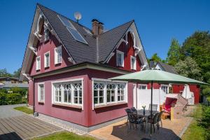 a red house with a table and an umbrella at Min Leefste in Prerow