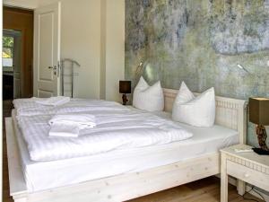 a bedroom with a white bed with a painting on the wall at Strandhus in Prerow