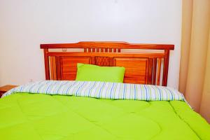 a green bed with a wooden headboard and a green pillow at Antoine in Taba