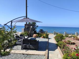 a patio with chairs and an umbrella and the ocean at liogerma i in Agios Ioannis Kaspaka