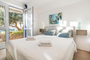 a white bedroom with a large bed with towels on it at Guest House Kovacevic in Hvar