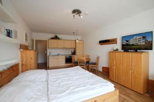 a bedroom with a large white bed and a kitchen at Haus Ostseeluft, Whg 4 Hühnergott in Baabe