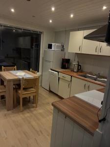 a kitchen with white cabinets and a table and a table and chairs at Sætervika Floating home in Hosen +4 photos