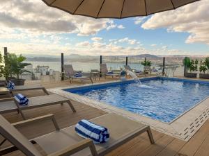 a pool with chairs and an umbrella on top of a building at Coral Beach Hotel & Spa in Aqaba