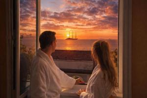 a man and woman looking out a window at a sailboat at Greif Hotel & Spa in Trieste