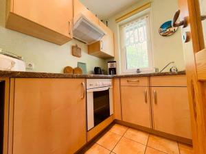 a kitchen with wooden cabinets and a stove top oven at Ferienwohnung Boston Terrier in Thiessow
