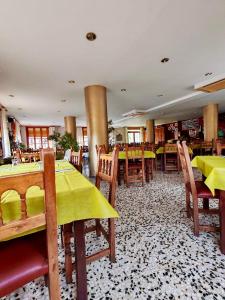 a restaurant with tables and chairs with yellow table cloth at Hotel Acebo & Natura in Castiello de Jaca