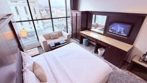 a bedroom with a bed and a tv and a couch at اجنحة الطائف للشقق المخدومة - AL Taif Suites in Taif