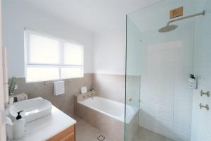a bathroom with a tub and a sink and a shower at Ocean Views Byron Infused Bliss NEW in Encounter Bay