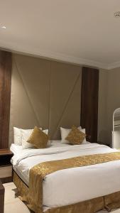 a bedroom with a large white bed with gold pillows at سما الخليج للشقق المخدومة in Hafr Al-Batin