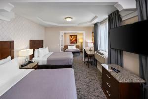 a hotel room with two beds and a desk at Quality Inn & Suites in Vancouver