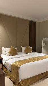 a large bed with gold sheets and pillows on it at سما الخليج للشقق المخدومة in Hafr Al-Batin +51 photos