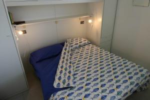 a small room with a bed with a blue comforter at Casa Onde & Tramonti in Marina di Grosseto