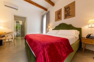 ein Schlafzimmer mit einem Bett, auf dem eine rote Decke liegt in der Unterkunft Itria Palace in Ragusa