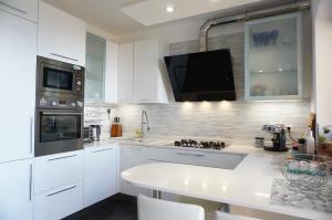 a kitchen with white cabinets and a tv on the wall at Casa Vista Mare in Muggia +14 photos