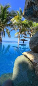 a swimming pool with palm trees and the ocean at Oceanfront Designer Penthouse, Private Pool in Ixtapa