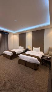 a hotel room with two beds and a chair at شقق بوابة العالية للشقق الفندقية in Medina
