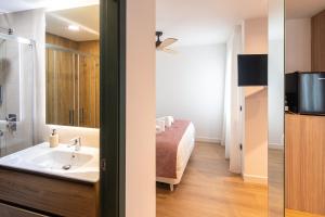 a bathroom with a bed and a sink and a television at Geysotur Ribera Luxury Suites in Córdoba +22 photos