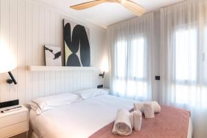 a white bedroom with a bed with towels on it at Geysotur Ribera Luxury Suites in Córdoba